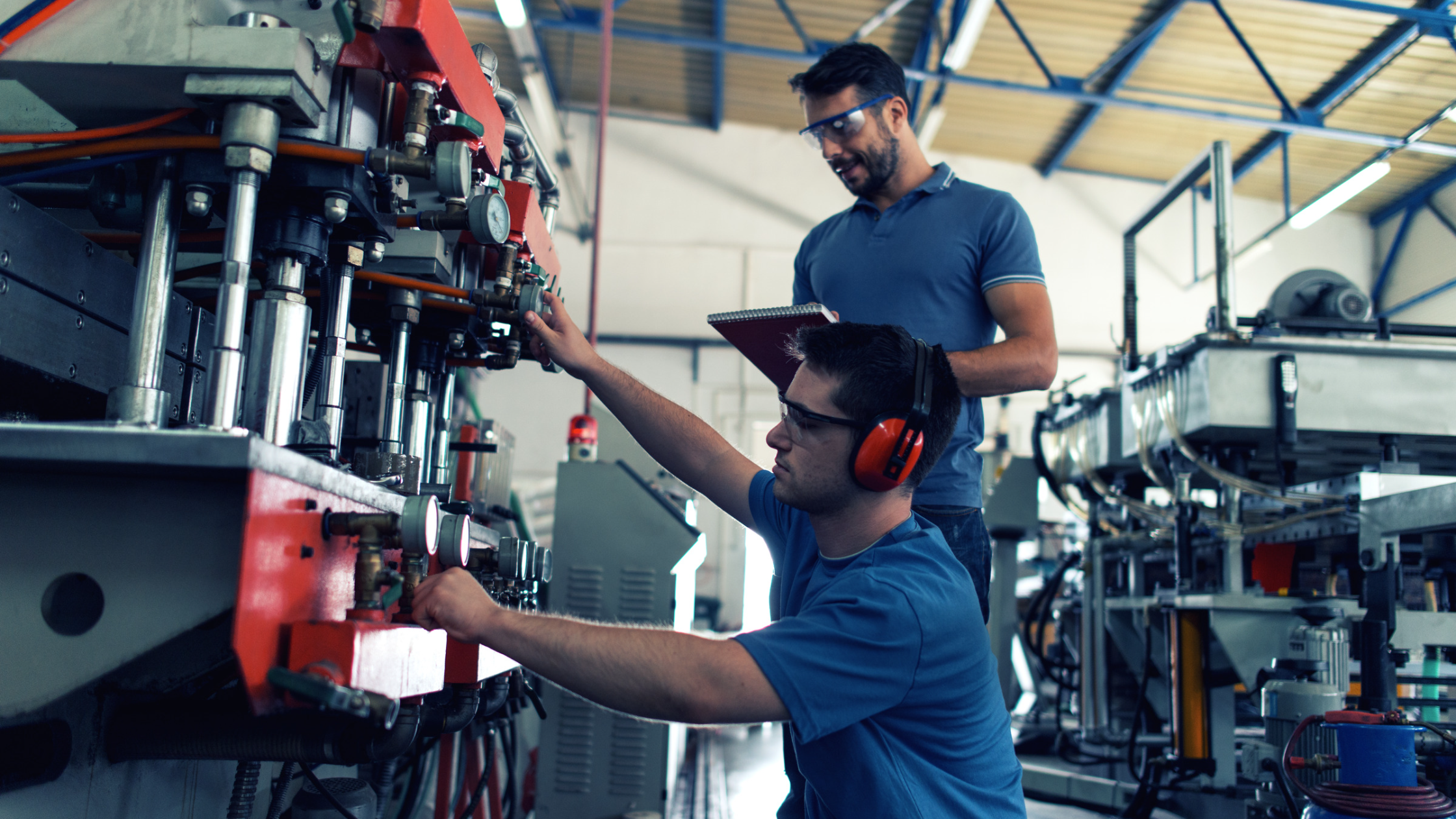 two man in a factory checking on a machine